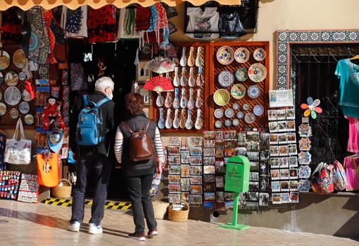 Una pareja de turistas observa una tienda de recuerdos en la zona de la Mezquita-Catedral