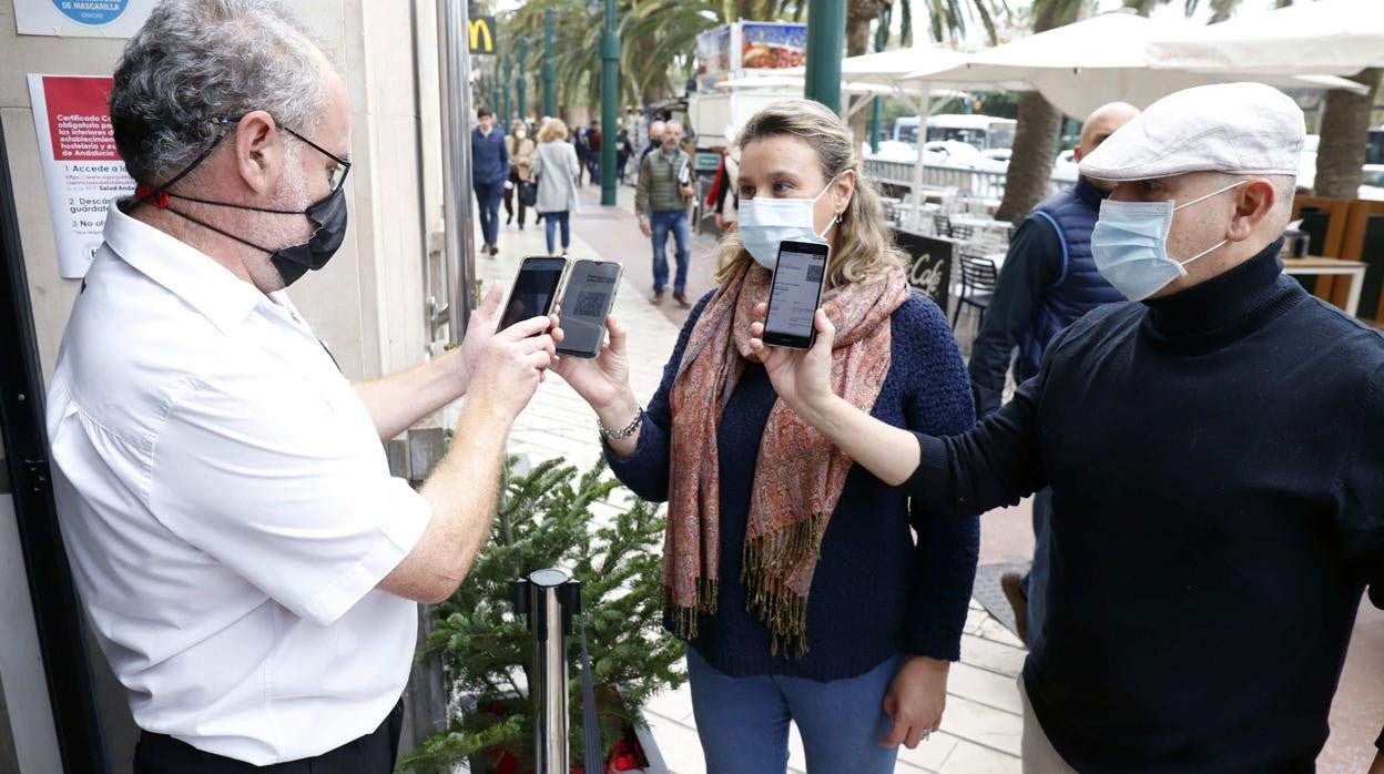 Dos ciudadanos presentan el pasaporte Covid a la entrada de un restaurante en Málaga