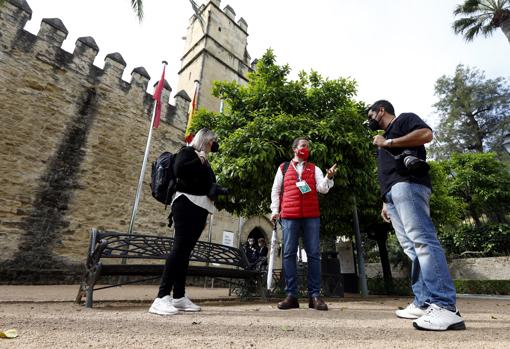 Un guía explica a una pareja de turistas el monumento del Alcázar