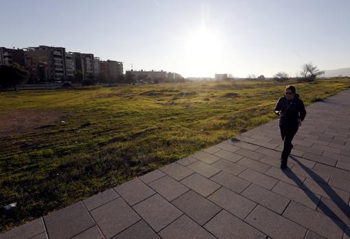 Una mujer pasa dealante de parte del terreno del futuro parque del Canal