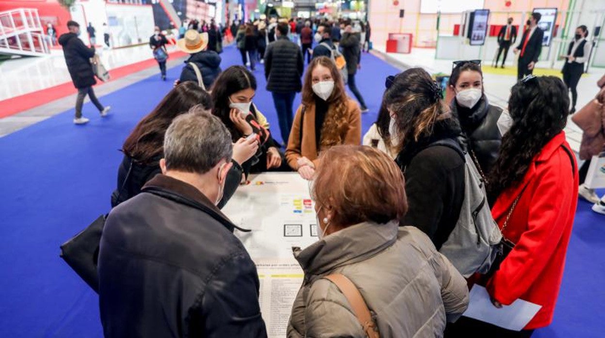 Un grupo de visitantes miran un mapa con recomendaciones turísticas en Fitur