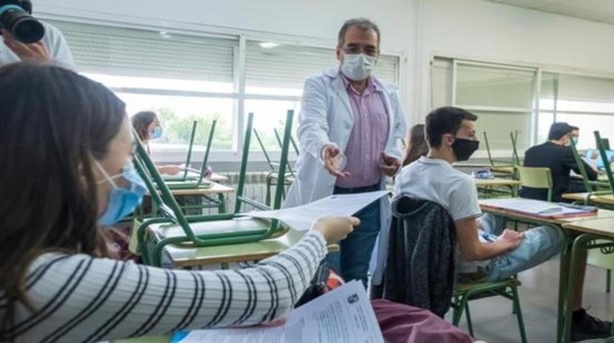 Un docente recoje trabajos en clase