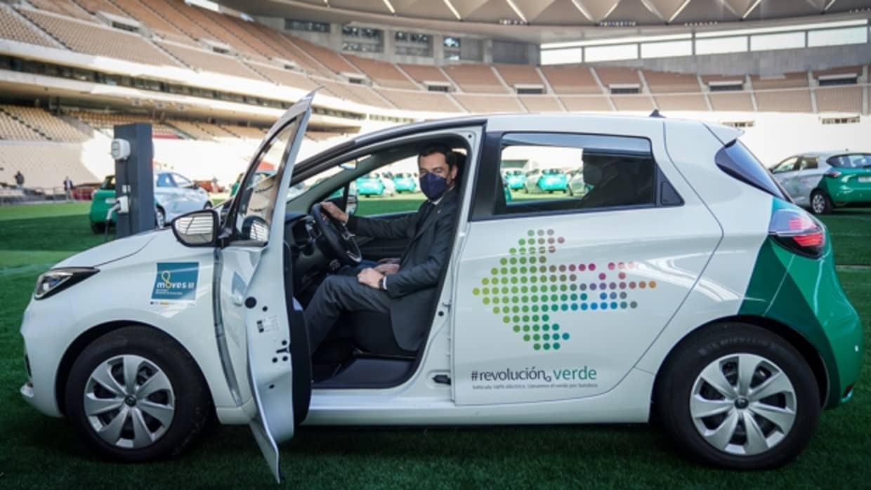 El presidente de la Junta, Juanma Moreno, en uno de los coches eléctricos durante la presentación de la flota en el estadio de la Cartuja de Sevilla