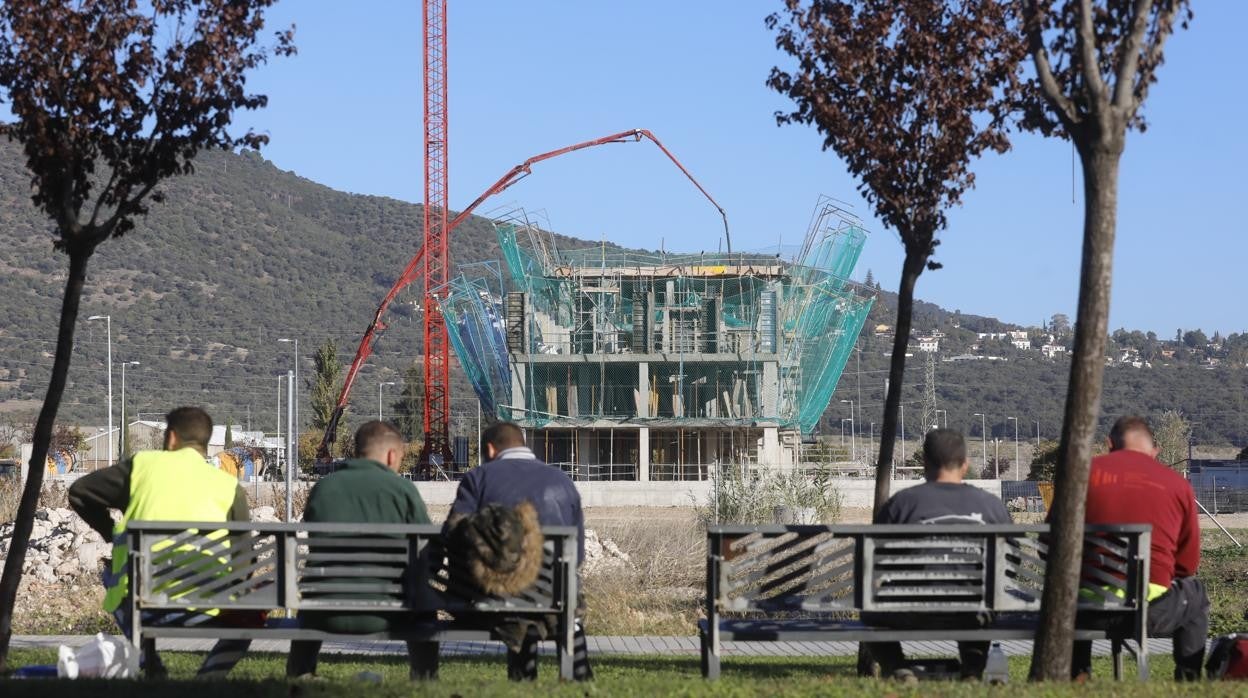 Un grupo de trabajadores de una promoción de viviendas en Córdoba descansa frente a un edificio en obras