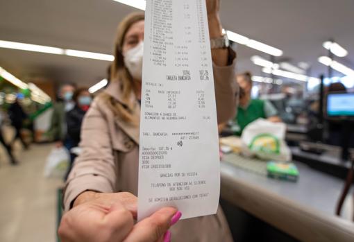 Una señora muestra su ticket de compra en un supermercado