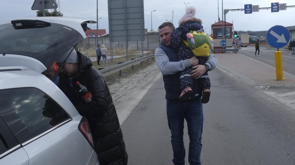 Un padre con su hijo en la frontera de Ucrania con Polonia tras estallar la guerra