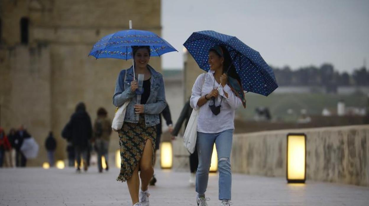 Dos jóvenes pasean por el Puente Romano en Córdoba