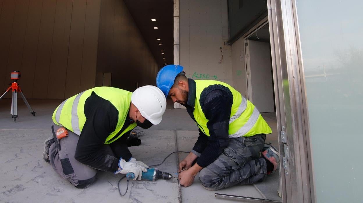 Dos operarios trabajan en las obras del Centro de Exposiciones, Ferias y Convenciones de Córdoba