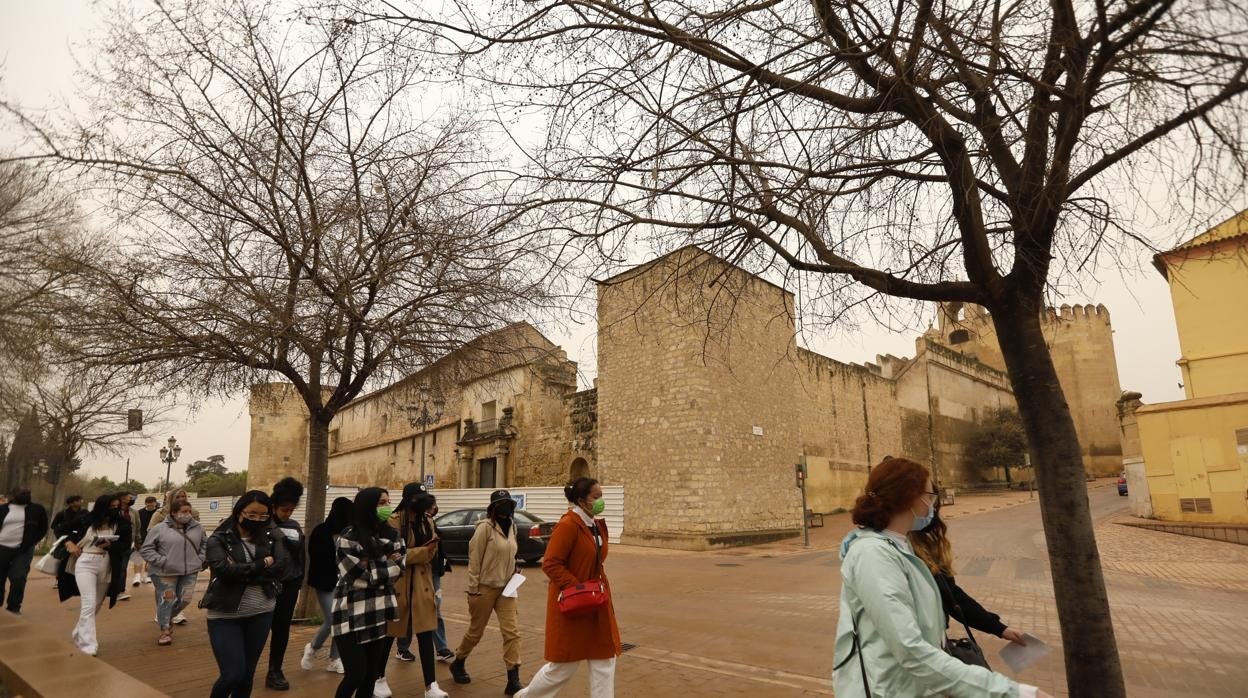 Un grupo de turistas pasa delante de la fachada sur del Alcázar de los Reyes Cristianos