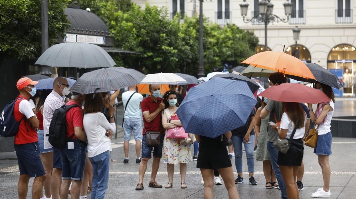 Un grupo de turistas con paraguas en la plaza de Las Tendillas