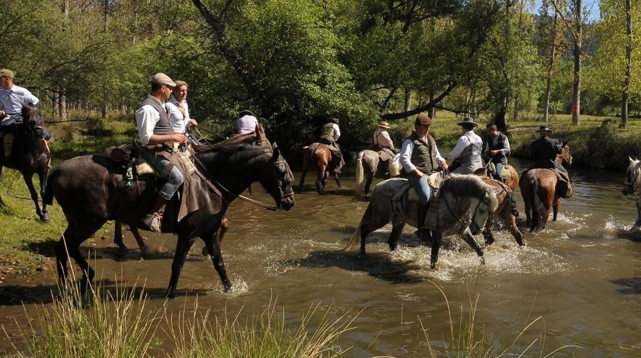 Fieles a caballo vadean el río Jándula de camino al santuario