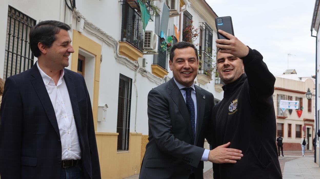 Un hombre se hace un 'selfie' con el presidente de la Junta de Andalucía, Juanma Moreno, en presencia del alcalde de Córdoba, José María Bellido