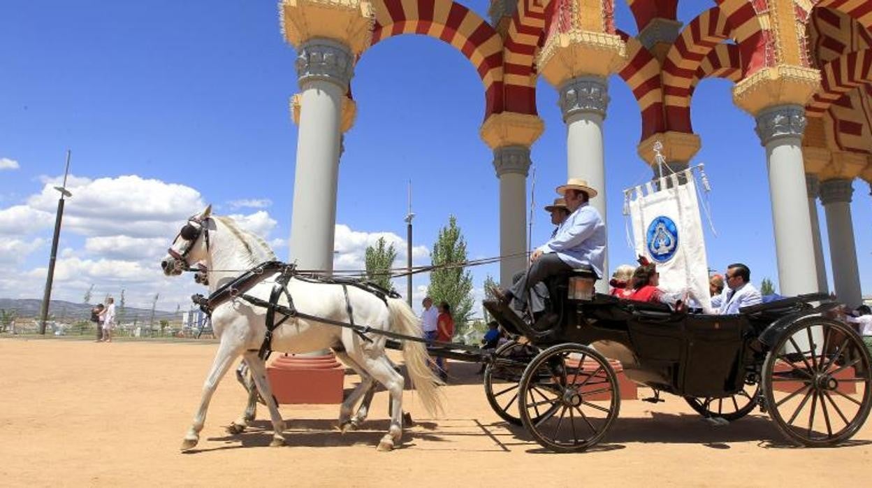 Una carruaje clásico pasa ante la portada de la Feria de Córdoba en una imagen de archivo