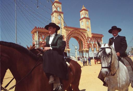 Dos caballistas pasan delante de la portada de la Feria de 2001