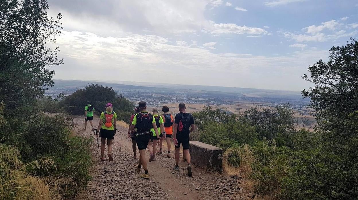 Senderistas bajan por la Cuesta del Reventón con la imagen de Córdoba al fondo