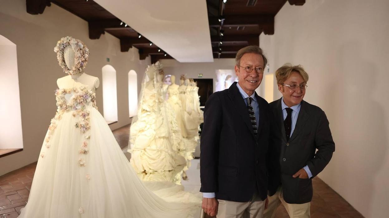 Los diseñadores Victorio y Lucchino posan con trajes de boda expuestos en el museo de Palma del Río (Córdoba)