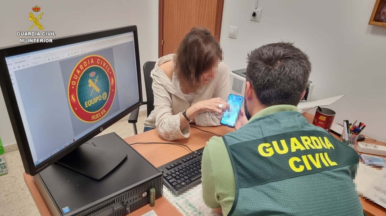 Una mujer muestra el contenido de su teléfono móvil a un agente de la Guardia Civil