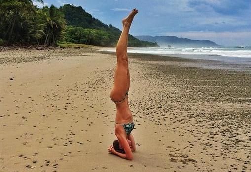 Giselle Bündchen haciendo yoga en una playa paradisiaca.