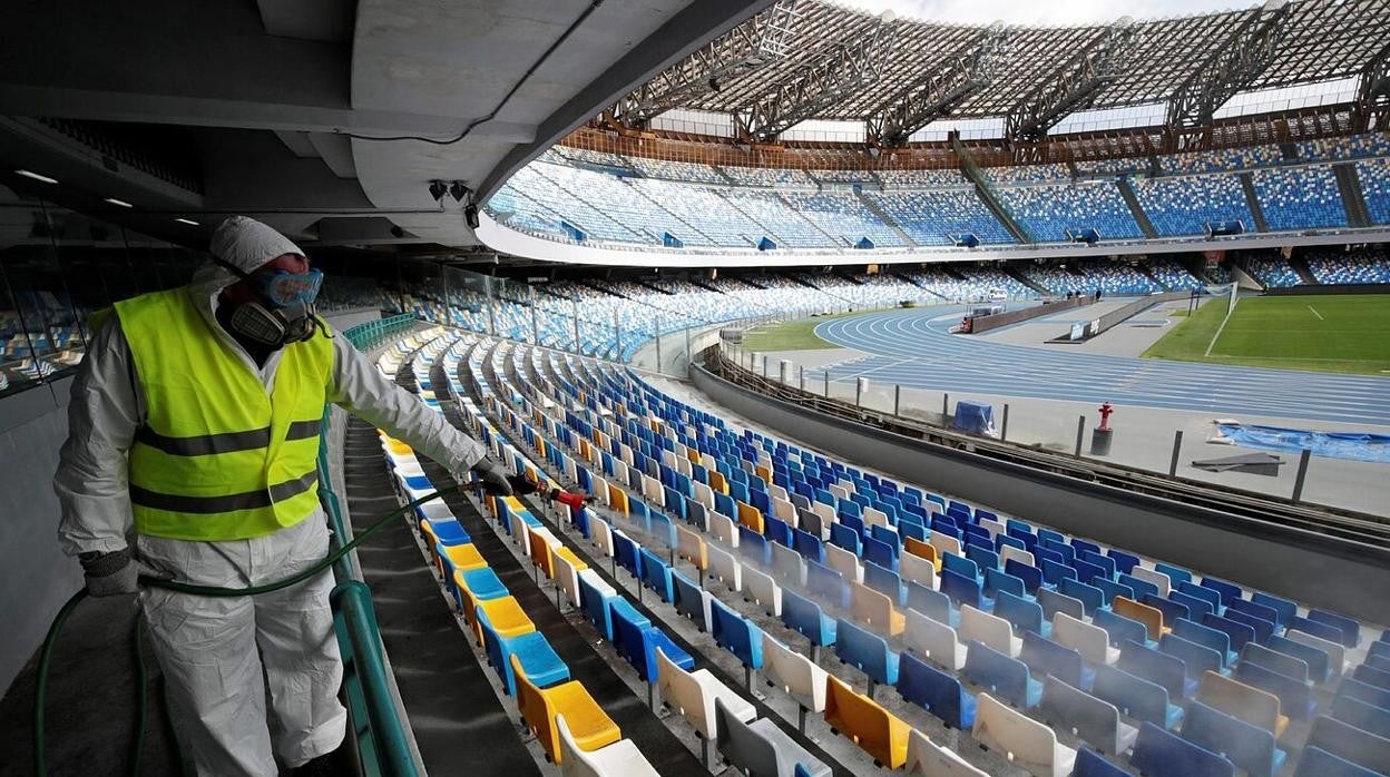 un operario desinfecta las gradas de un estadio.