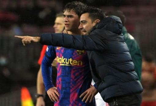 Gavi recibe instrucciones de Xavi con el Barça.