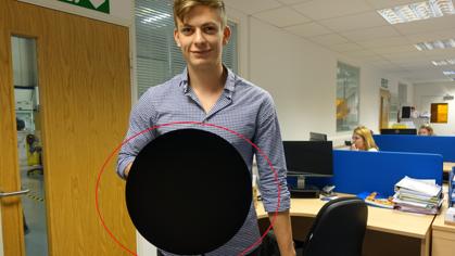 Un investigador sostiene un objeto circular rociado con «Vantablack»