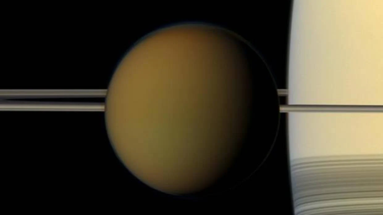 Titán en frente de los anillos de Saturno, el planeta que se ve a la derecha