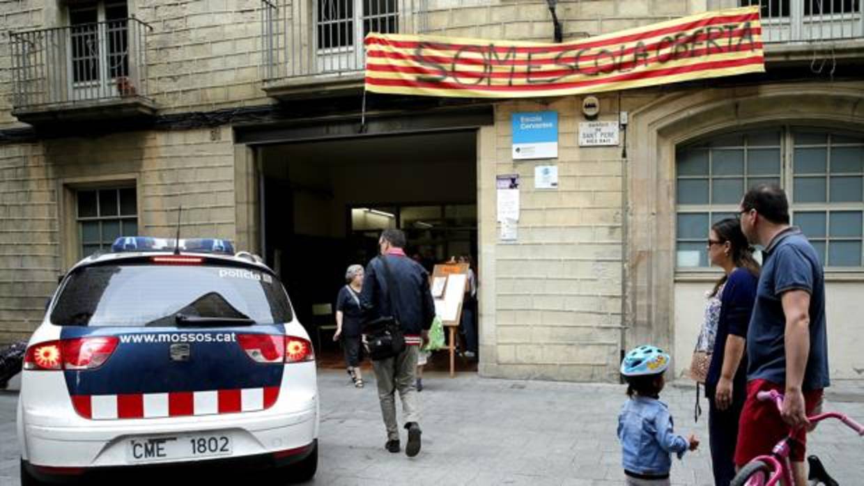 Un vehiculo de los Mossos d'Esquadra a la entrada del colegio público Cervantes de Barcelona que permanece abierto hoy sábado