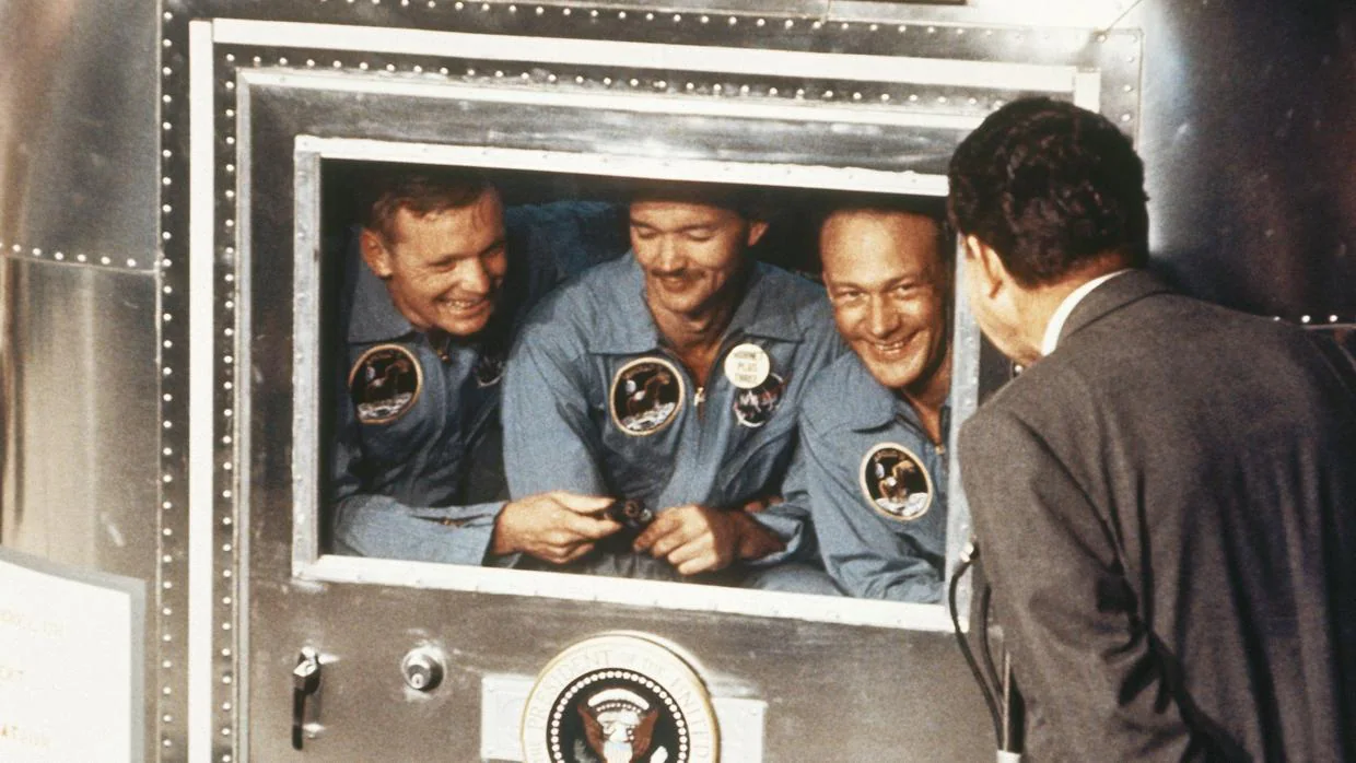Nixon saluda a los tres astronautas del Apolo 11 en su cuarentena, tras su regreso a la Tierra