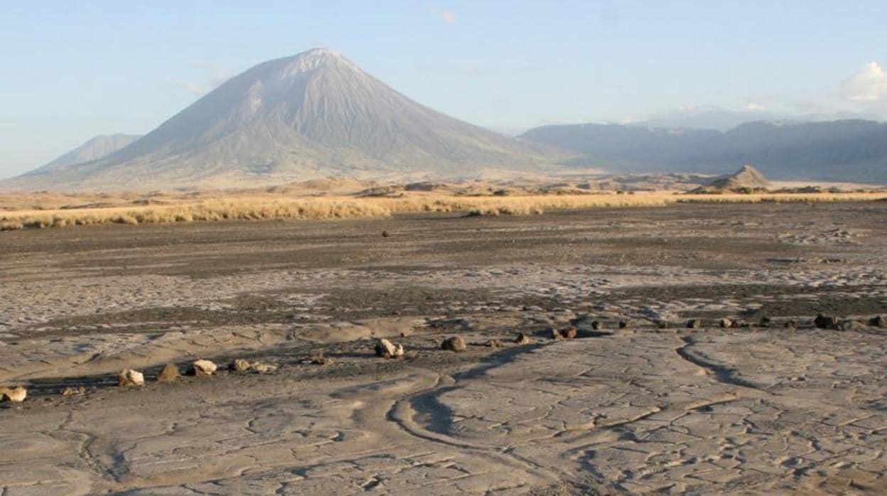 Vista de Engare Sero con huellas en un antiguo flujo de lodo volcánico en primer plano y el volcán Oldoinyo L'engai, al fondo