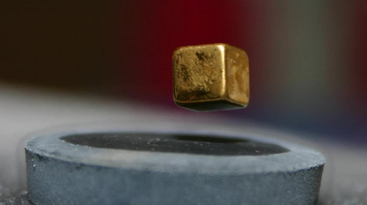 Fotografía de un imán levitando sobre un material superconductor