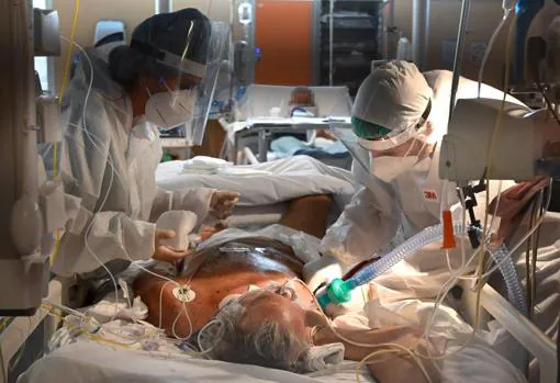 Dos trabajadores sanitarios atienden a un paciente de COVID-19 en una UCI del hospital Casal Palocco, cerca de Roma, este jueves