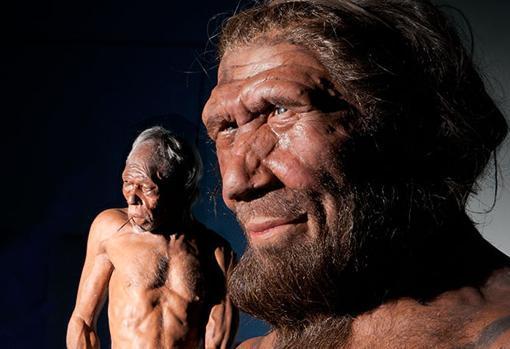 En primer plano, representación de un neandertal. Al fondo a la izquierda, un sapien