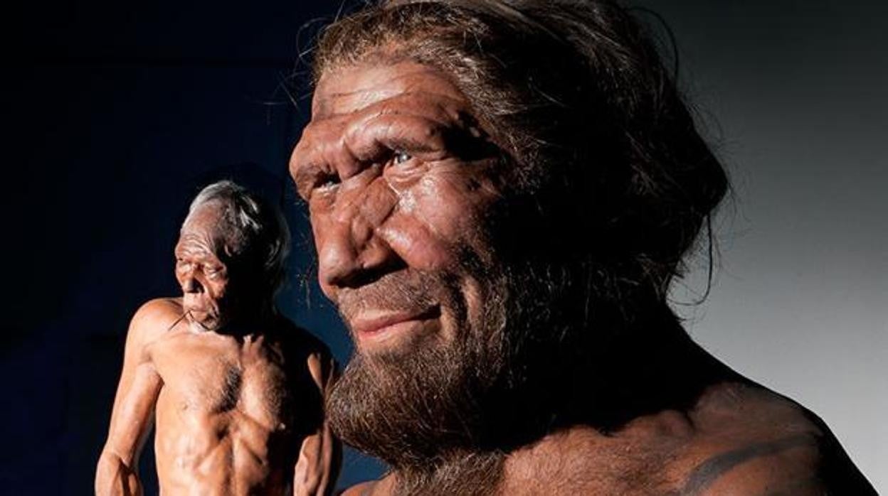 En primer plano, representación de un neandertal. Al fondo a la izquierda, un sapiens