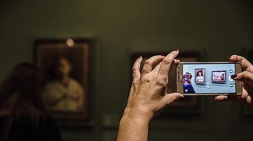 Una mujer toma una fotografía de dos de los cuadros