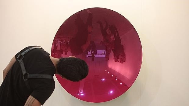 Un joven busca su imagen en una de las obras de Anish Kapoor