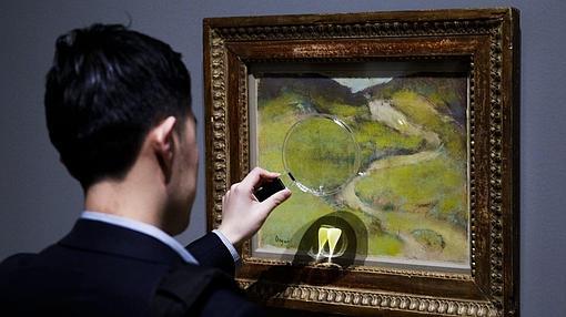 Un hombre usa una lupa para apreciar todos los detalles de una obra de Degas