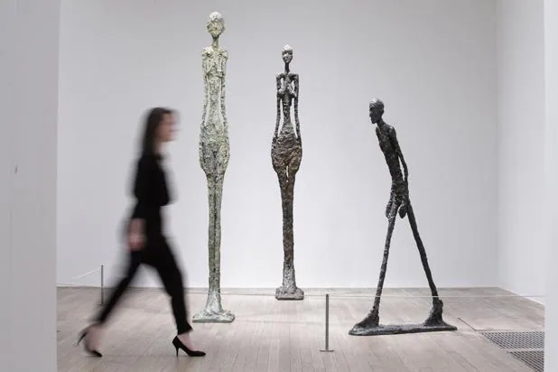 Una mujer pasea ante varias esculturas de Giacometti