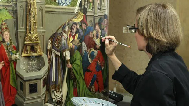 Una restauradora del Prado trabaja en el cuadro atribuido al taller de Jan van Eyck «La Fuente de la Gracia» en el taller de Restauración de la pinacoteca, que hoy ha abierto sus puertas con motivo de la presentación de su próxima Cátedra
