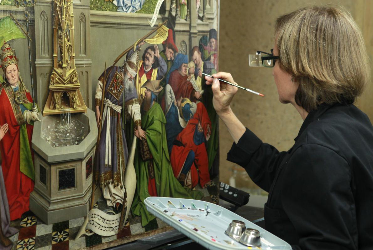 Una restauradora del Prado trabaja en el cuadro atribuido al taller de Jan van Eyck «La Fuente de la Gracia» en el taller de Restauración de la pinacoteca, que hoy ha abierto sus puertas con motivo de la presentación de su próxima Cátedra