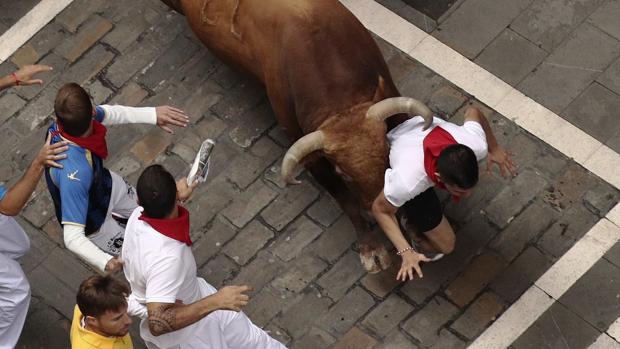 Un toro de Núñez del Cuvillo empuja a un corredor en el encierro