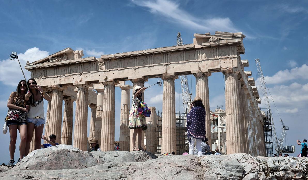 Un grupo de turistas se fotografían frente al Acrópolis de Atenas