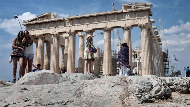 Un grupo de turistas se fotografían frente al Acrópolis de Atenas