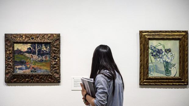 Una mujer observa 'Mujeres a la orilla del rio' de Gauguin (i) y 'Naturaleza muerta, jarrón con claveles' de van Gogh
