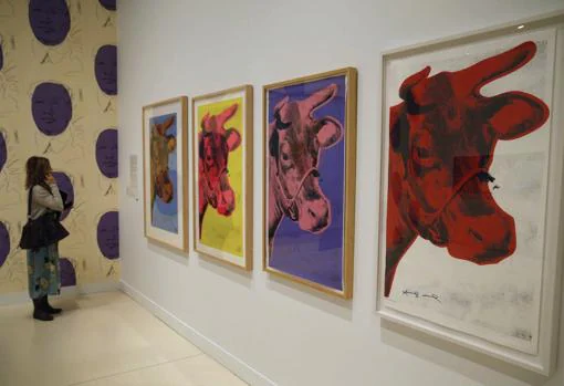 Una mujer observa varias «Vacas», de Warhol en la exposición «Andy Warhol. El arte mecánico» en CaixaForum Madrid