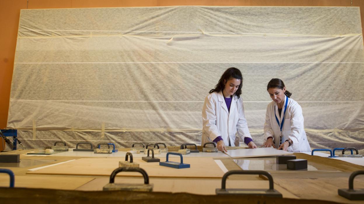 Irene García Bustos, a la izquierda, y María Jofre restauran el lienzo con el que Elías Salaverría conmemoró la gesta de Elcano en 1919