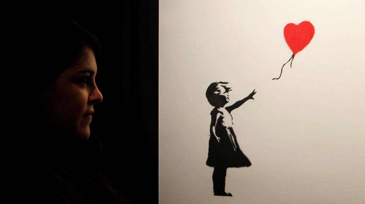 Una joven contempla «Niña con globo», una de las imágenes más icónicas de Banksy
