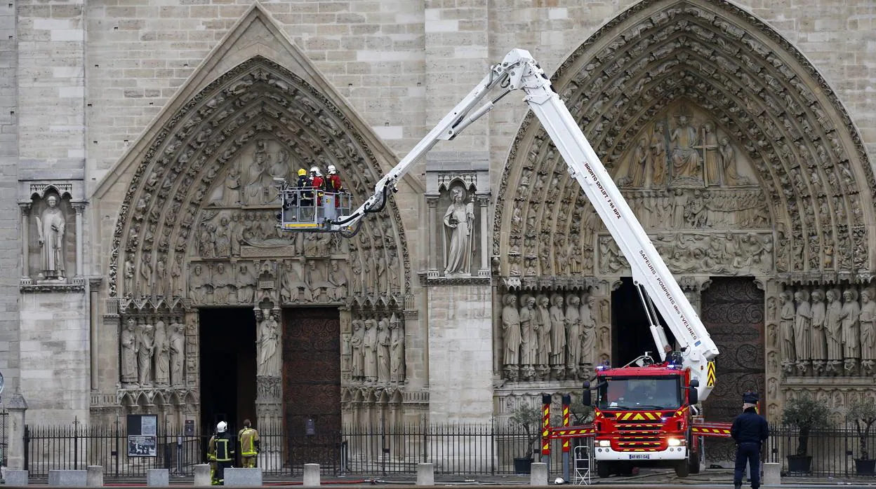 Varios bomberos trabajan en un elevador a la fachada de catedral de Notre Dame, este martes en París (Francia)