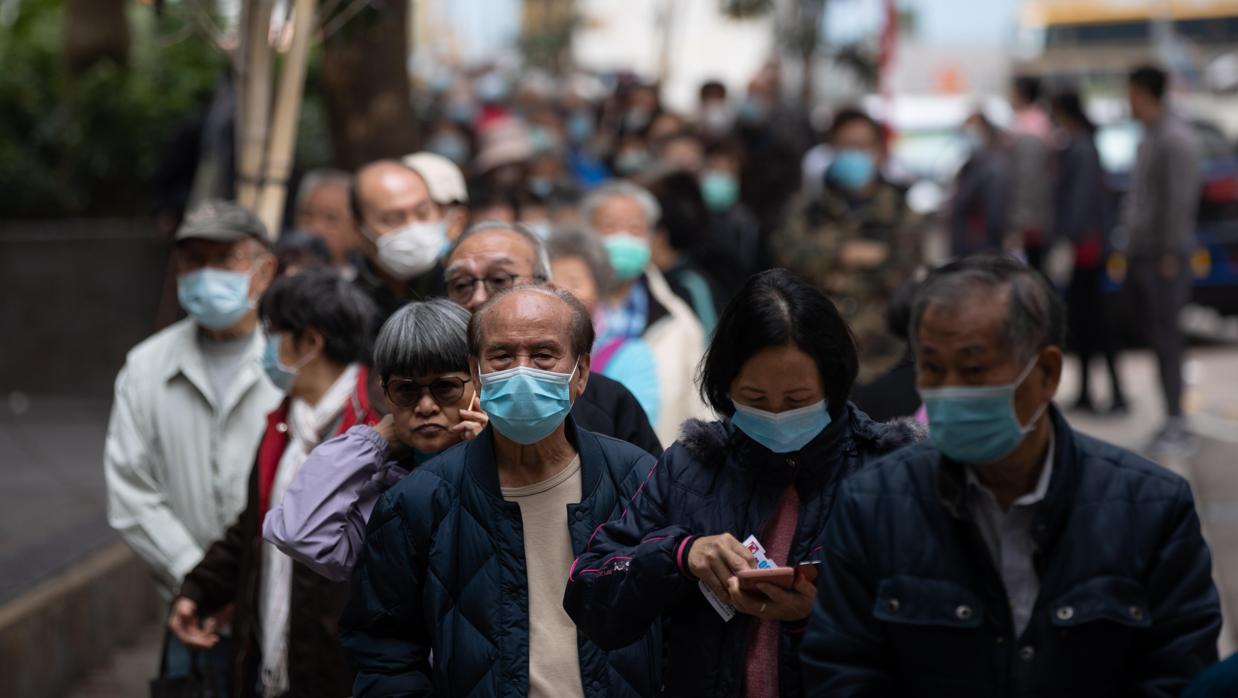 Varios hongkoneses hacen hacen fila para recibir máscaras faciales gratuitas de una cadena de tiendas