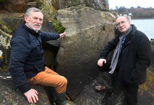 Los franceses Robert Faligot (derecha) y Noel Rene Toudic posan cerca de la roca inscrita que descifraron en Plougastel-Daaoulas