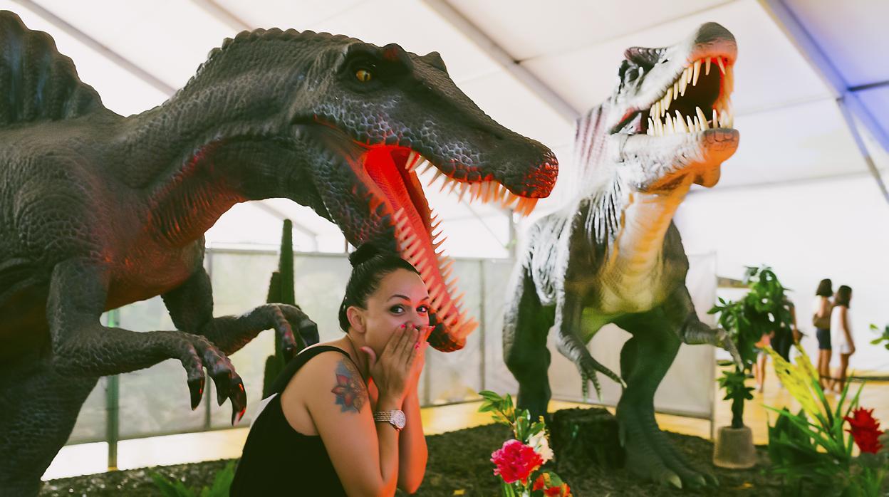 Una visitante fotografiada junto a dos dinosaurios de la exposición